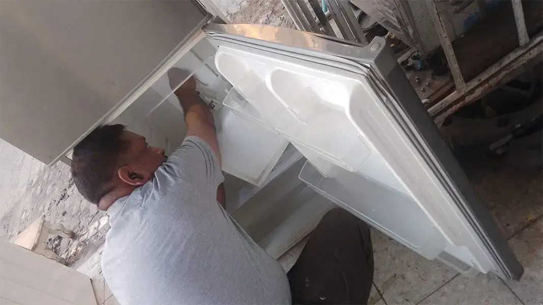 فني تصليح ثلاجات يفحص عطل التبريد داخل المنزل في الكويت